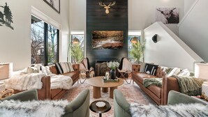 Un salon moderne avec une cheminée, des canapés en cuir et une grande décoration représentant une tête de cerf.