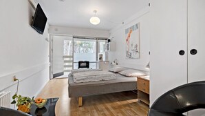 A modern bedroom with a bed, bedside table, lamp, and a TV mounted on the wall.