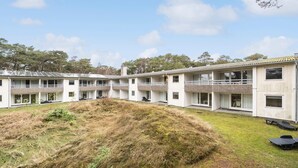 A modern, multi-story building with a flat roof, large windows, and a grassy courtyard.