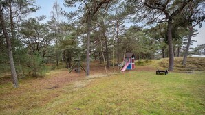 A playground with a swing set and a slide, surrounded by trees.