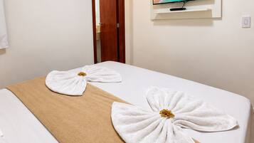 A hotel room with a bed, a TV mounted on the wall, and a door leading to another room.