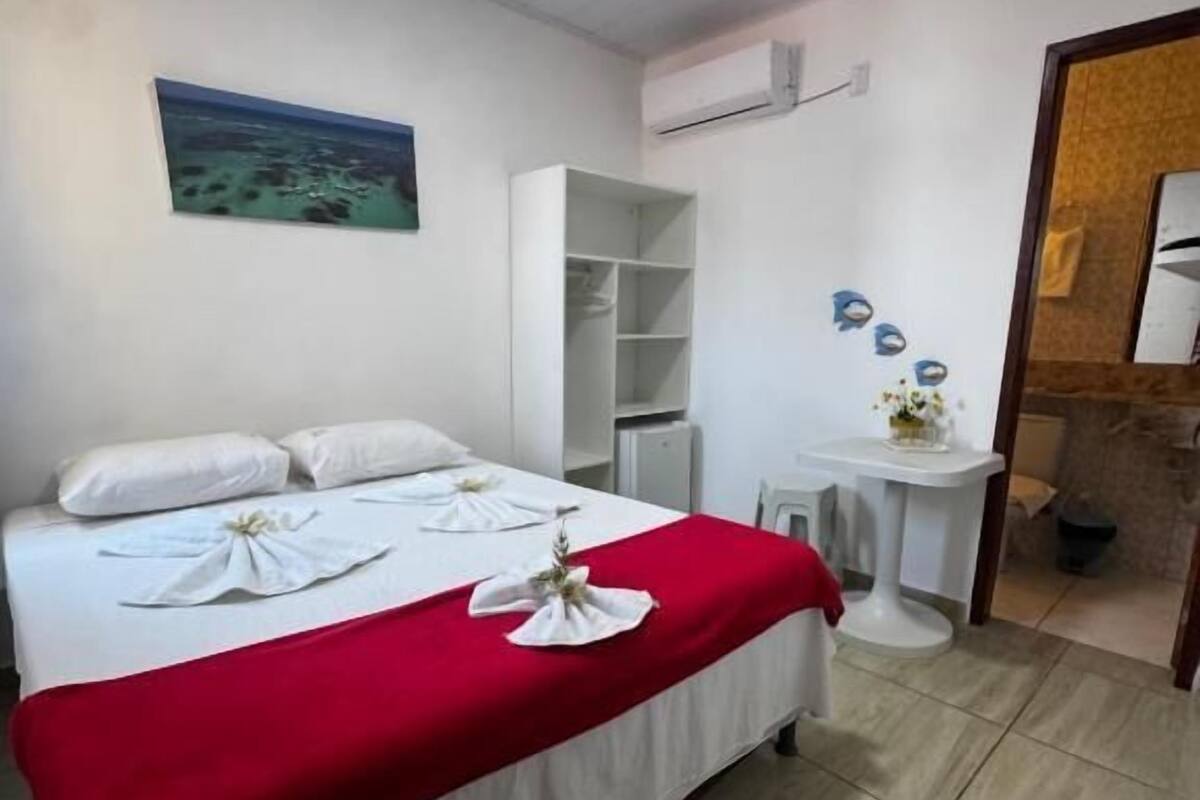 Une chambre d’hôtel avec un lit, une petite table ronde, une armoire et un tableau au mur.