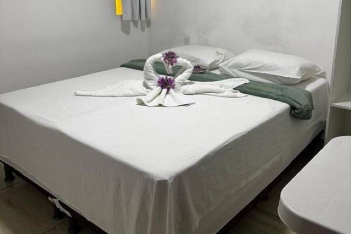 Une chambre d’hôtel avec un lit, un tableau, un appareil de climatisation et un rideau.