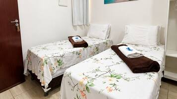 Habitación de hotel con dos camas, una puerta, un equipo de aire acondicionado, un cuadro de playa y una cortina blanca.