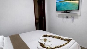 Habitación de hotel con cama, televisor montado en la pared y aire acondicionado.
