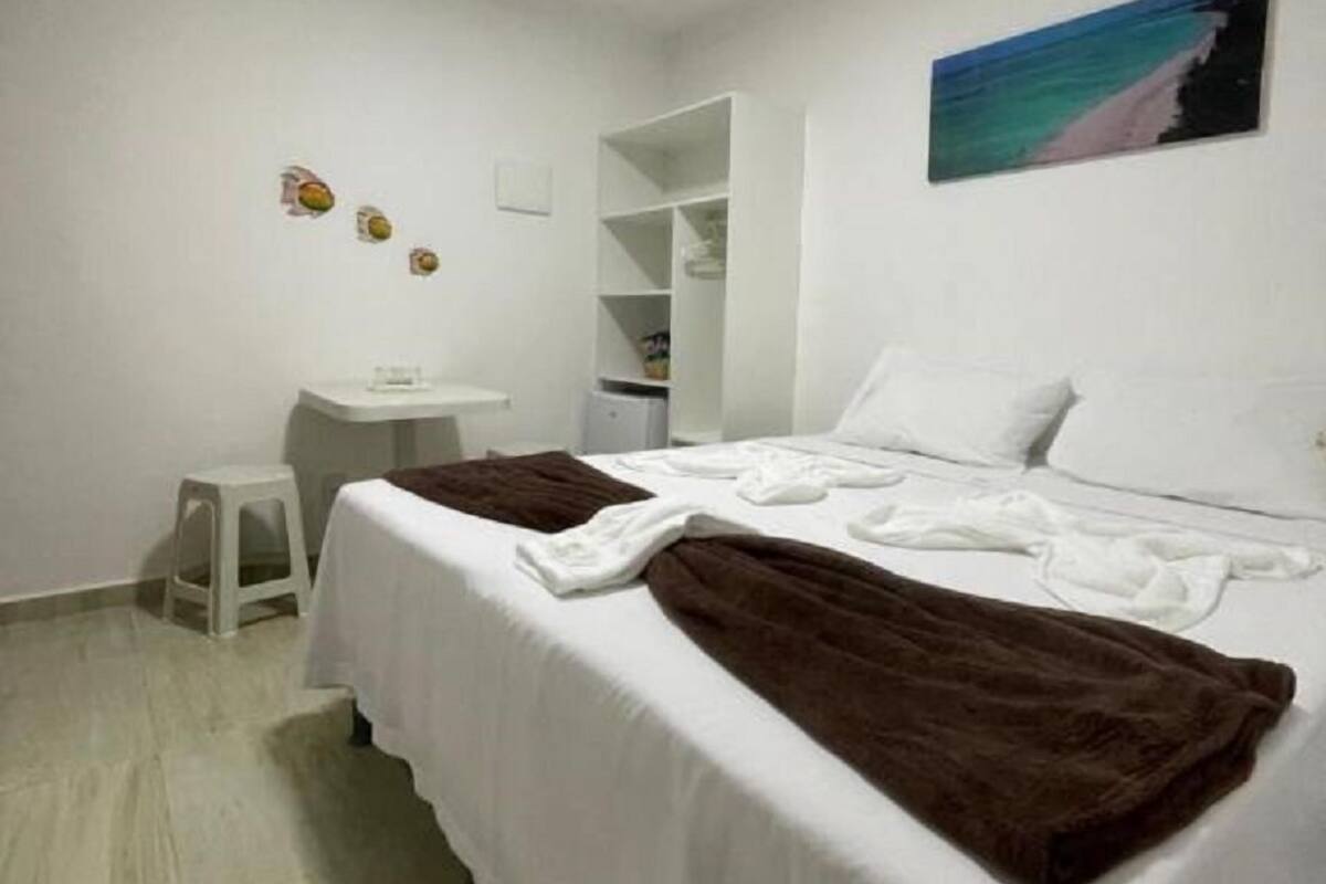 Une chambre à coucher avec un lit, un bureau, une chaise et un tableau accroché au mur.