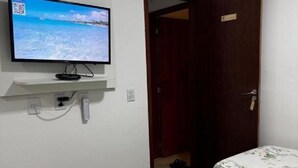 Una habitación con dos camas, un televisor en la pared y una puerta que da a otra estancia.