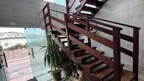 Una escalera moderna con barandillas de madera, plantas en macetas y vistas al exterior.