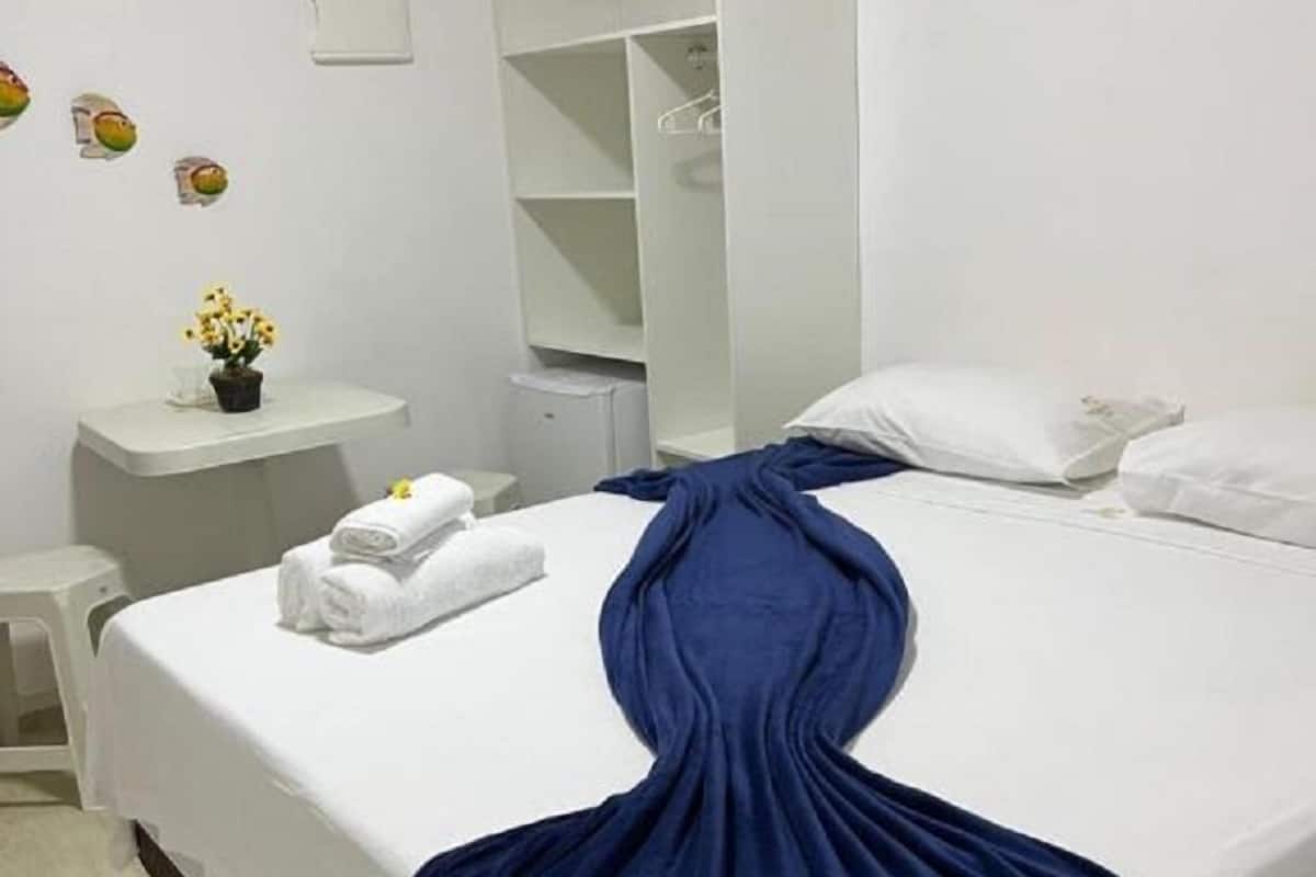 Une chambre d’hôtel avec un lit, un bureau blanc, un miroir et un tableau accroché au mur.