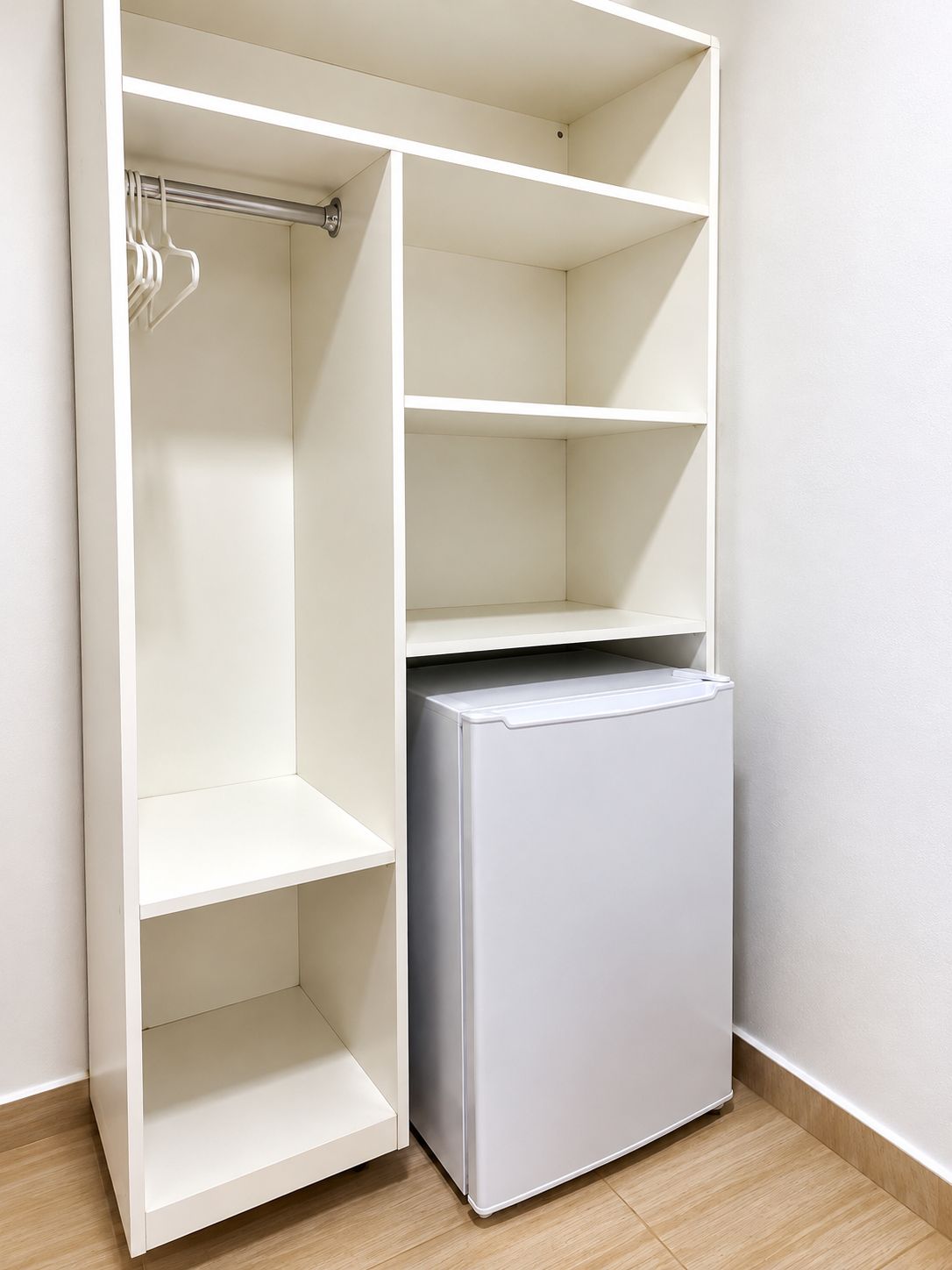A white wardrobe with open doors, revealing shelves and hanging space.