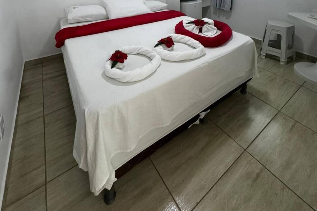 Une chambre d’hôtel avec un lit, un bureau, une chaise, une fenêtre et un tableau au mur.
