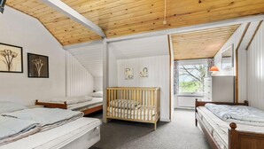 Een slaapkamer met drie bedden, een wieg en een kast.