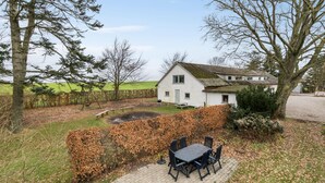 Een wit huis met een tuin, een schommel en een picknicktafel.