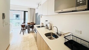 Een moderne keuken met een ingebouwde magnetron, een spoelbak en een eethoek met een tafel en stoelen.