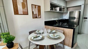 Μια σύγχρονη κουζίνα με μια κεντρική νησίδα, συσκευές από ανοξείδωτο ατσάλι και μια τραπεζαρία διαμορφωμένη για τέσσερα άτομα, με ένα στρογγυλό τραπέζι και καρέκλες.