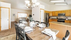 A modern kitchen with wooden cabinets, a central island, stainless steel appliances, and a chandelier.