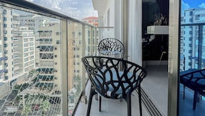 Un balcón con una silla, una mesa y vistas de la ciudad.