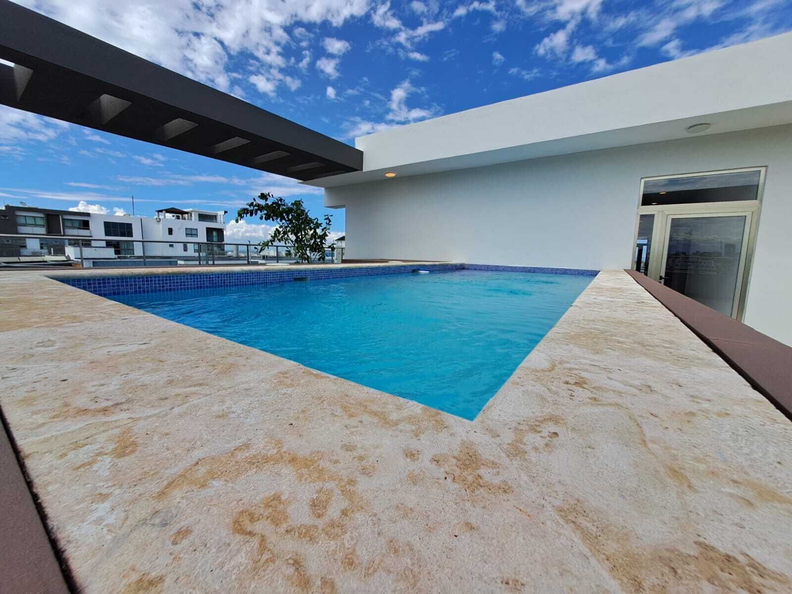 A rooftop swimming pool with a clear blue sky in the background.