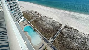 Een hoog hotel met uitzicht op het strand, een zwembad en een zandstrand.