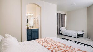A bedroom with a bed, a nightstand, a dresser, and a mirror.