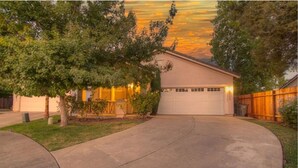 A residential house with a garage, driveway, and surrounding trees.