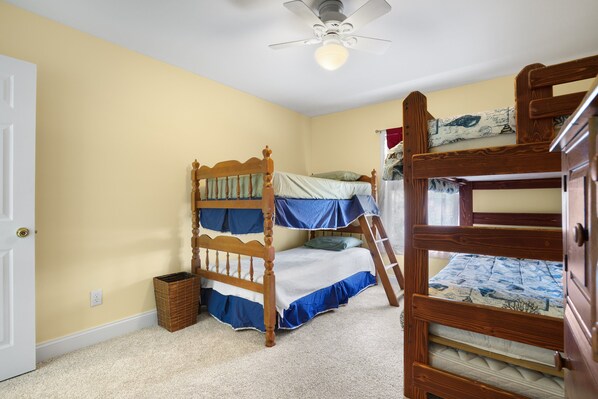 Une chambre avec un lit superposé, un ventilateur de plafond et une porte.