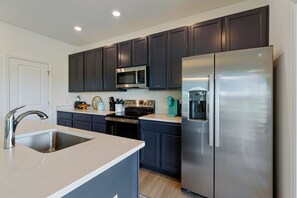 A modern kitchen with dark cabinetry, stainless steel appliances, and a built-in microwave.