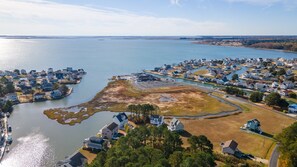 An aerial view of a coastal residential area with houses, a marina, and a large body of water.