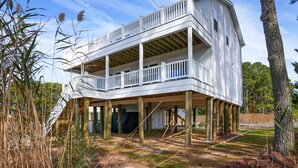 Ein zweistöckiges Haus mit Balkon, Holzterrasse und überdachter Eingangshalle.