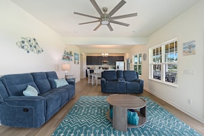 A living room with a ceiling fan, a sofa, a coffee table, and a rug.