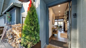 A modern building entrance with a wooden log display, a Christmas tree, and a well-lit interior.