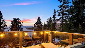 A glass-enclosed balcony with a view of a snowy landscape and trees at dusk.