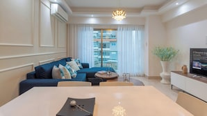A modern living room with a sofa, dining table, and a TV. - Amazing Harmony Apt 12FLR in LaJulia @Pool*Gym*Spa (Santo Domingo)