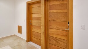 Two wooden doors with a simple design, a small vent on the wall, and a light switch. - Amazing Harmony Apt 12FLR in LaJulia @Pool*Gym*Spa (Santo Domingo)
