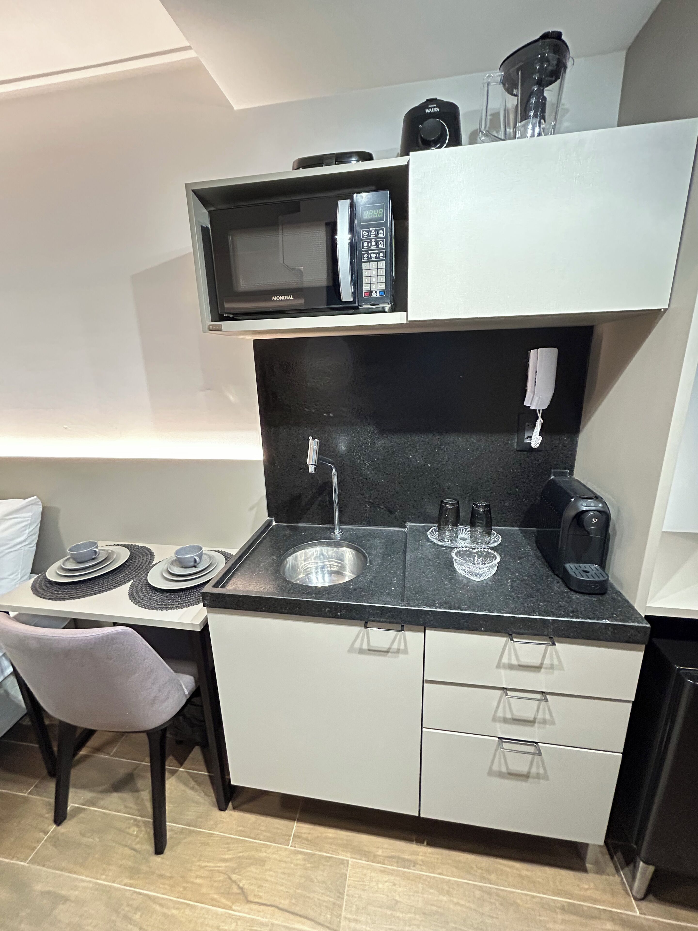 Una cocina compacta con microondas, cafetera y lavabo.