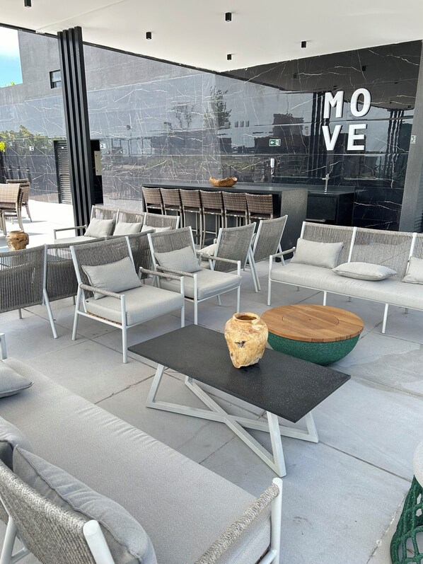 An outdoor seating area with wicker chairs and a bar. - Melhores Flats (João Pessoa)