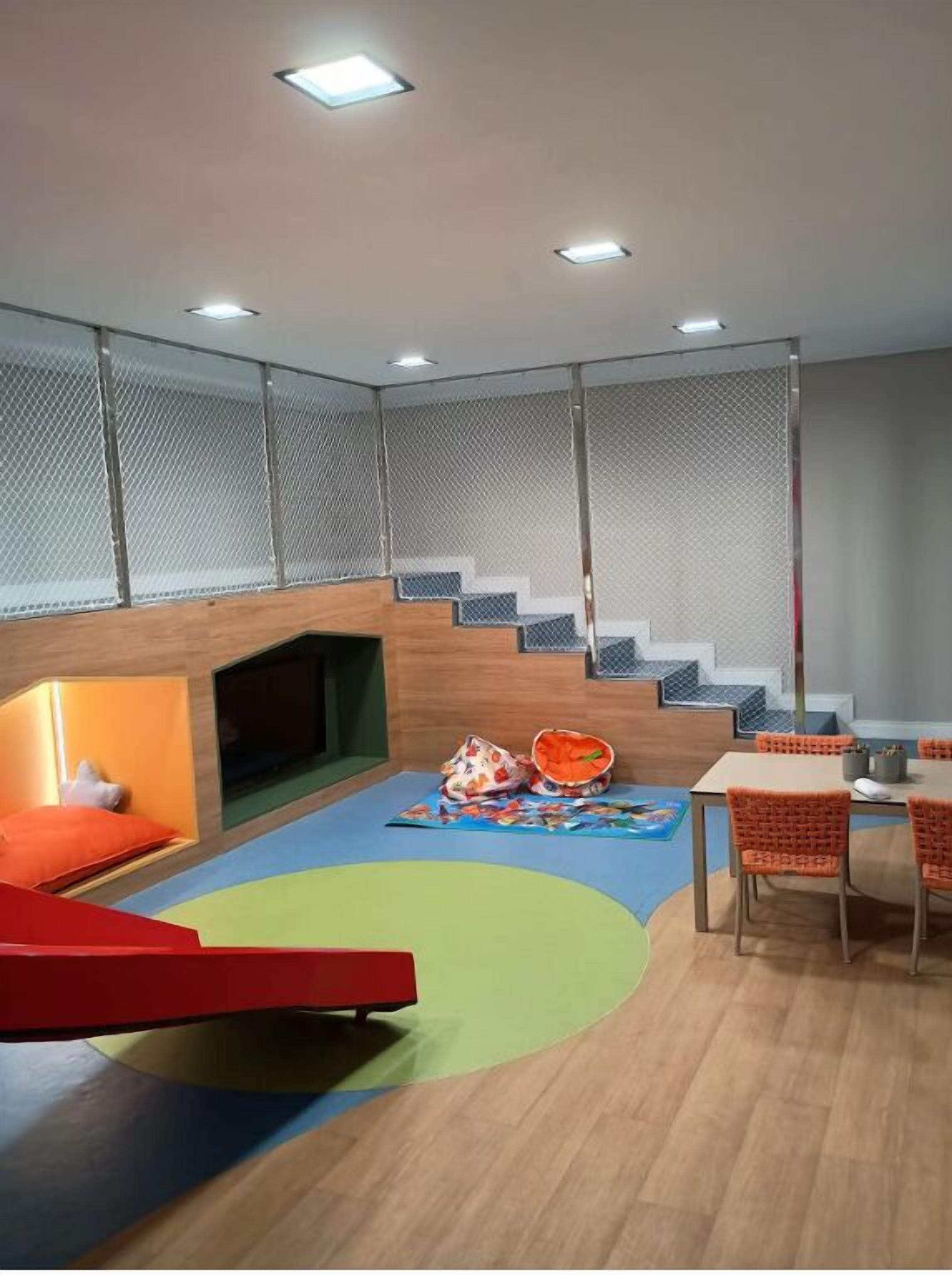 Ein Kinderspielbereich mit Rutsche, Krabbeldecke und einem Tisch mit Stühlen.