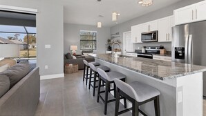 A modern kitchen with a central island, bar stools, and stainless steel appliances. - Punta Gorda Private Pool Vacation Home (Punta Gorda)