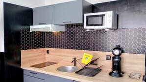 A modern kitchen with a wooden countertop, a built-in microwave, and a coffee machine. - “black studio”, wifi, Bollaert, 3 pers, RDC (Lens)