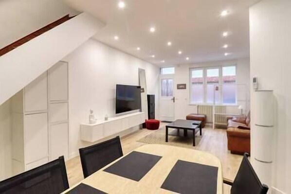 Relax in this stylish living room with a flat-screen TV, comfortable seating area, and dining table.