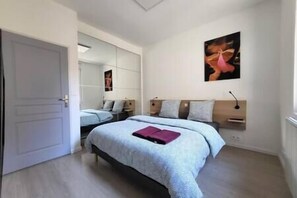 Relax in a serene bedroom with a large bed, bedside table, and wall-mounted artwork.