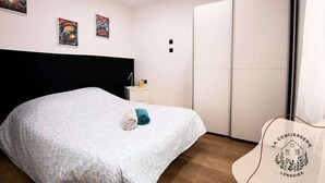 Une chambre à coucher avec un lit, une table de chevet et une armoire. Il y a trois tableaux accrochés au mur.