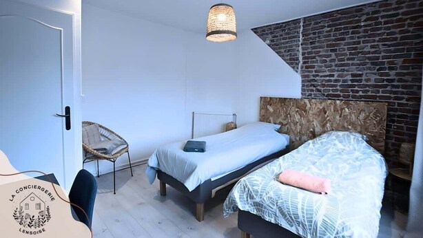 A bedroom with a bed, a chair, and a hanging light fixture. - La maison citadine, garage, wifi, lavelinge, 4pers (Lens)