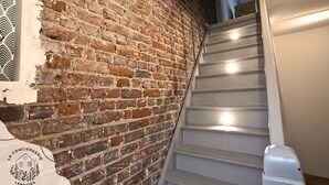 A staircase with a brick wall on one side and a white wall on the other. - La maison citadine, garage, wifi, lavelinge, 4pers (Lens)