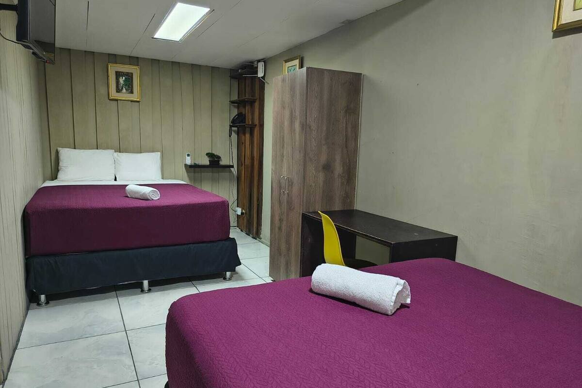 Une chambre d’hôtel avec deux lits, une armoire en bois, un bureau et une chaise.