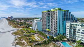 Un hotel moderno de altura con varios balcones, piscina y vista al mar.