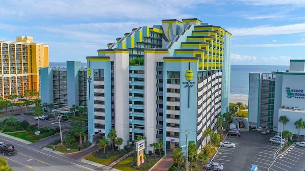 Un hotel de varios pisos con un diseño moderno, con balcones y un letrero llamativo.