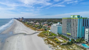 Un hotel frente al mar con vistas a la playa, varios pisos y una piscina.