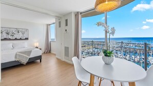 Ein modernes Hotelzimmer mit Bett, Esstisch und Blick auf den Hafen.
