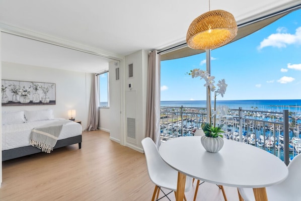 A modern hotel room with a bed, a dining table, and a view of the marina.
